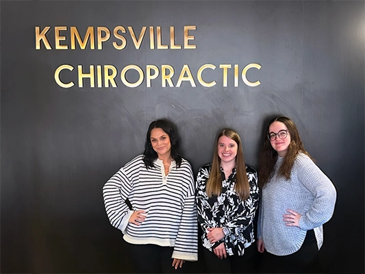 Chiropractic Virginia Beach VA Staff In Front Of Wall Logo